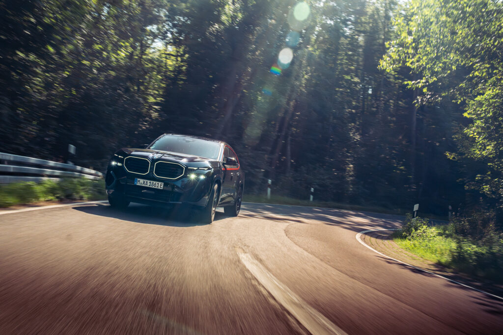 Schwarzer BMW XM in der Waldkurve im Gegenlicht, Rolling Shot von der M Drive Tour der BMW Niederlassung Hannover