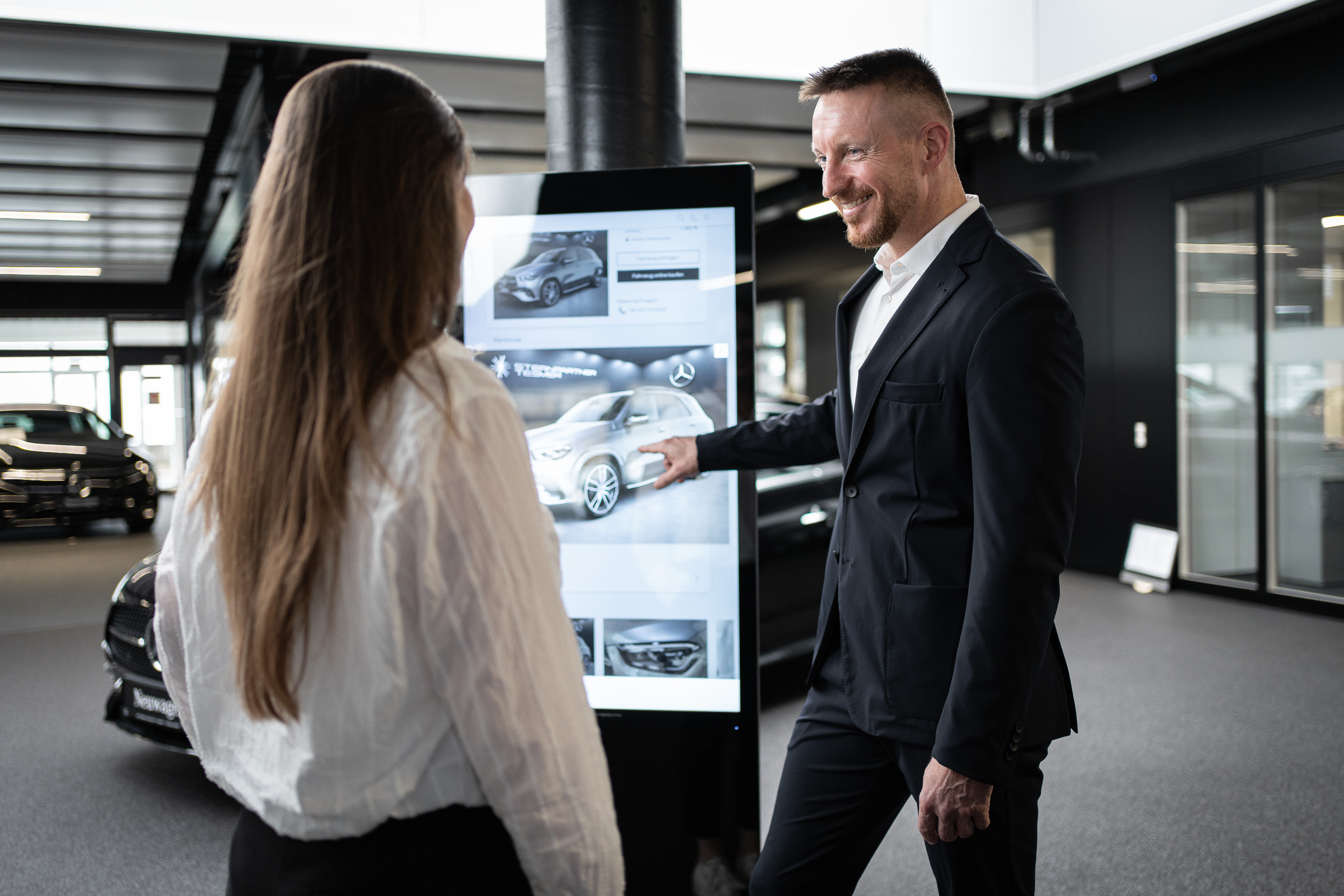 Verkäufer und Kollegin am digitalen Display im Showroom von Sternpartner Tesmer